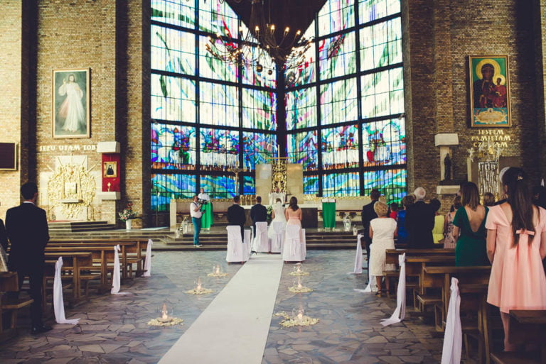 Wnętrze kościoła w Rypinie podczas ślubu: para przy ołtarzu i witraże
