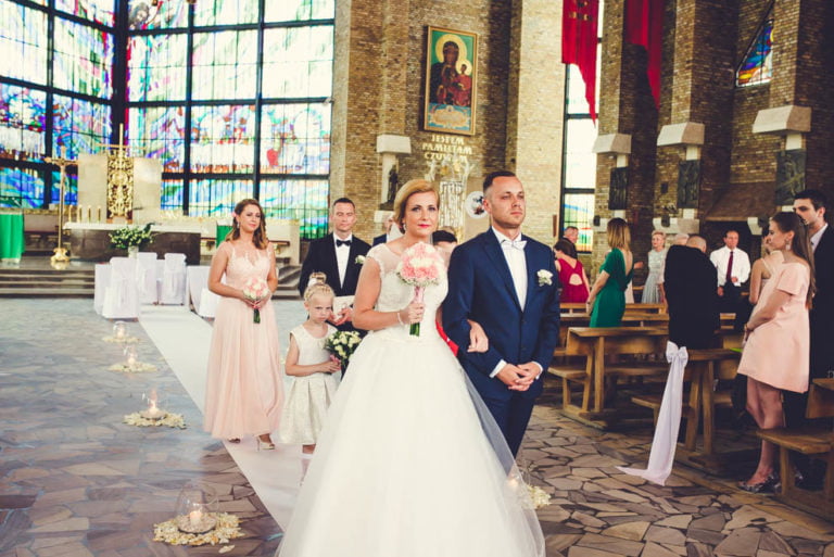 Para młoda z bukietem w nawie kościoła, za nimi druhny