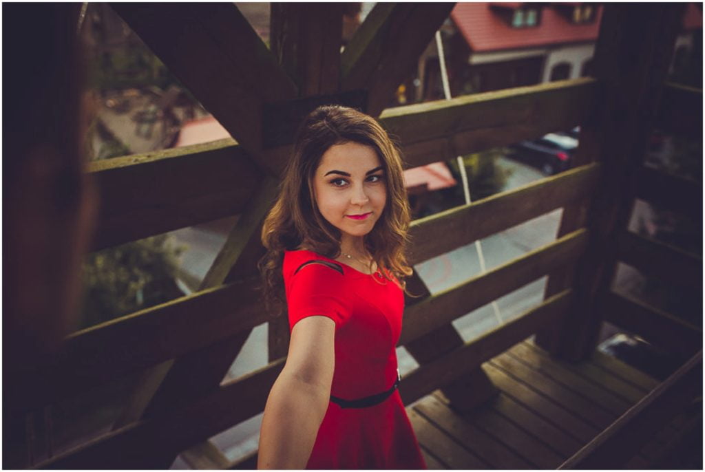 Sesja narzeczeńska w Osadzie Karbówko — co ubrać i zabrać? Portret kobiety w czerwonej sukience na tarasie