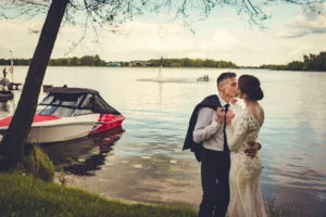 Fotograf na ślub w Skrwilnie: o co zapytać przed rezerwacją? Pocałunek pary młodej nad jeziorem – fotografia ślubna