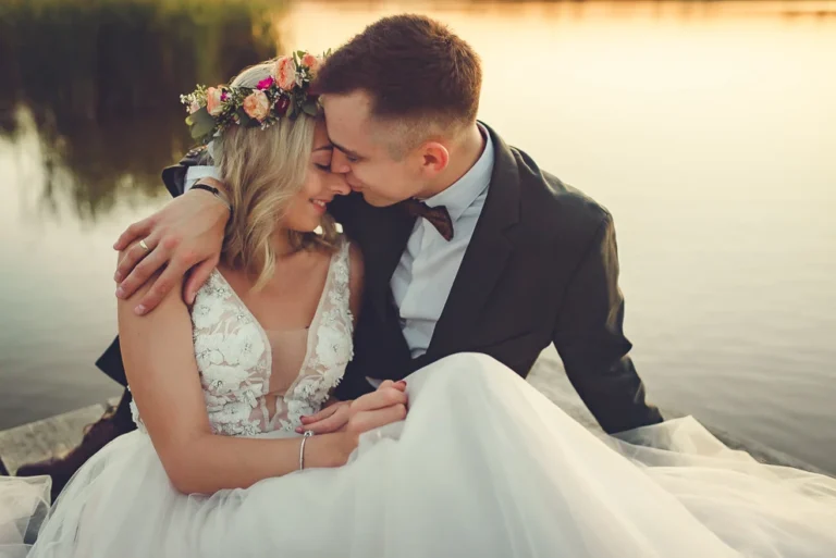 Para młoda w objęciach nad wodą o zachodzie słońca